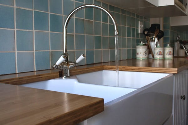 bamboo countertops with white farmhouse sink, blue tile backsplash