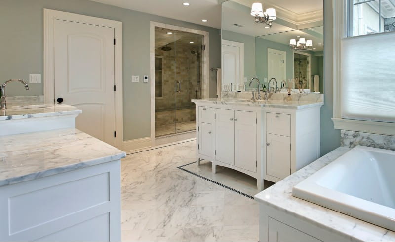 Carrara marble natural stone flooring and countertops in spa-like white bathroom