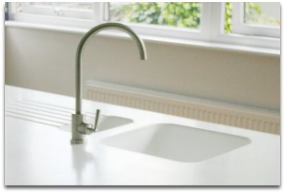 Corian sink molded into white countertops with drain board