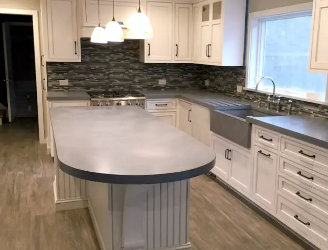 curved concrete countertops on kitchen island with white cabinets