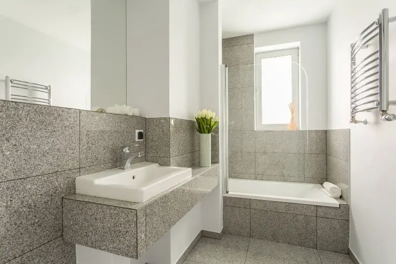 gray granite tile bathroom countertop, floor tiles, and tub surround with white sink and tub