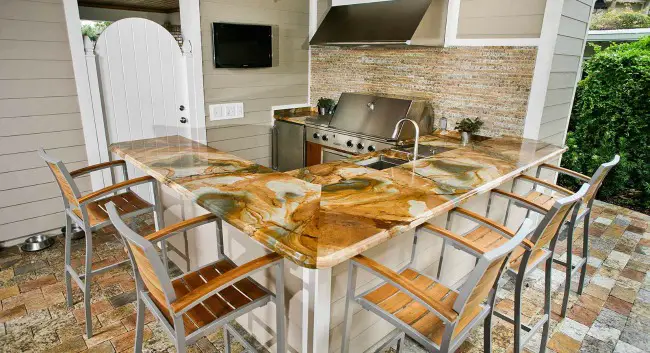 Marble outdoor kitchen countertops. Luxury outdoor kitchen with fridge and stainless barbecue grill.