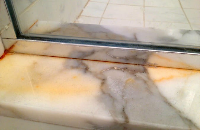 yellow-brown rust stain in marble shower door stop