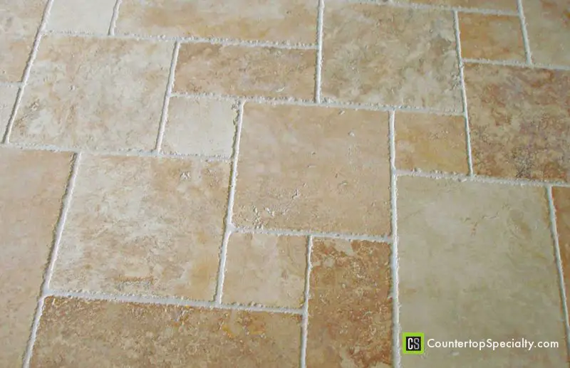 Tumbled travertine tile floor with a rustic finish and French pattern.