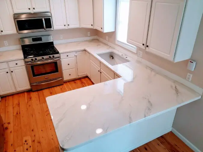 white epoxy countertops look like carrara marble on white cabinets with wood floor