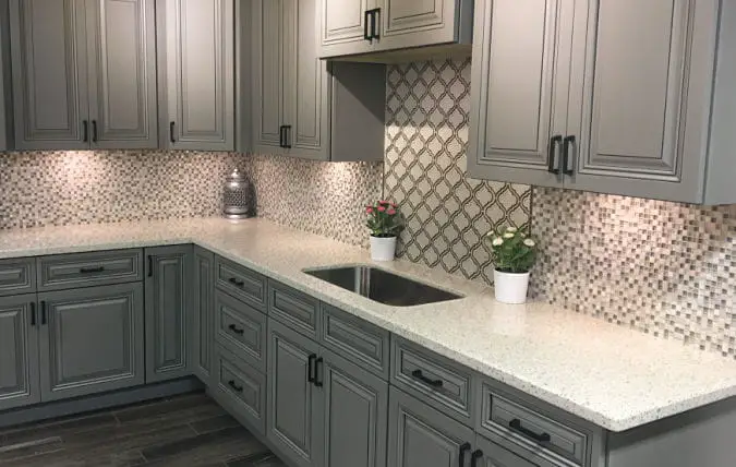 white quartz countertops on gray cabinets with glass tile backsplash